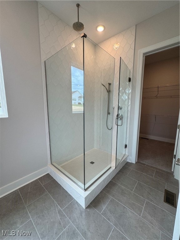 bathroom with a shower with door and tile patterned floors