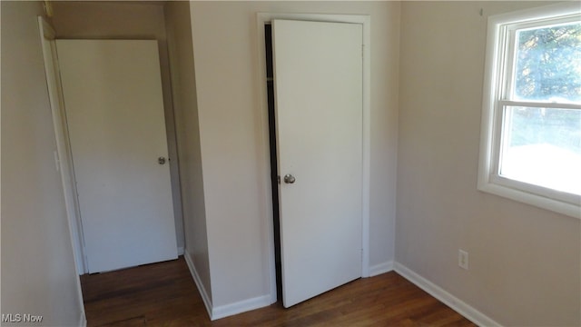 unfurnished bedroom featuring multiple windows and dark hardwood / wood-style flooring