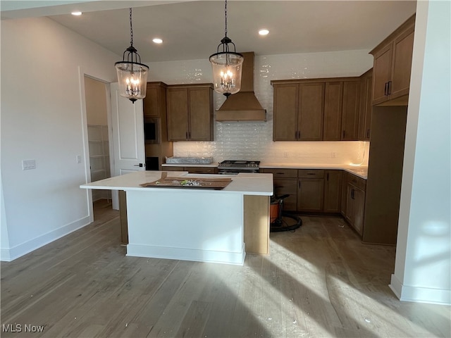 kitchen with light hardwood / wood-style flooring, black gas range oven, custom exhaust hood, and a kitchen island