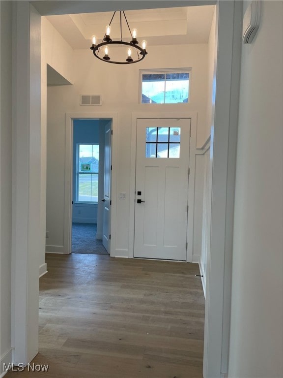 entrance foyer featuring hardwood / wood-style flooring, a tray ceiling, and a chandelier