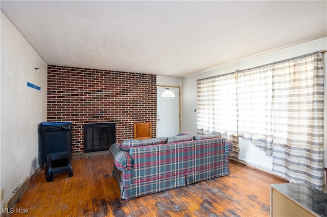 living room featuring dark wood-type flooring and a brick fireplace