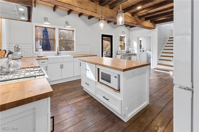 kitchen featuring white cabinetry, sink, a kitchen island, and butcher block countertops