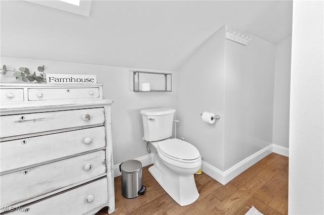 bathroom with toilet, lofted ceiling with skylight, hardwood / wood-style floors, and vanity