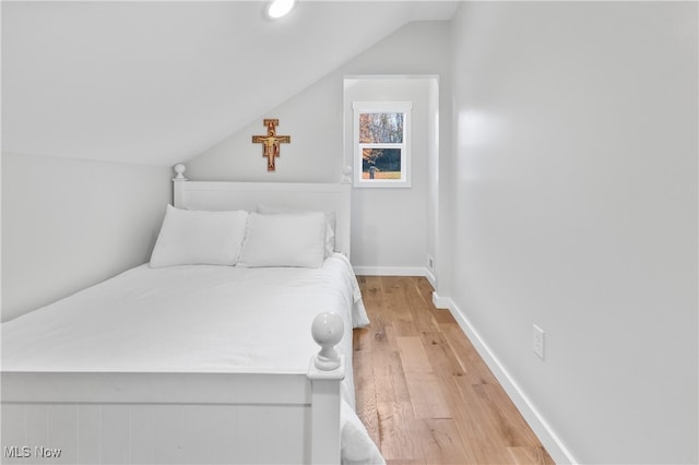 bedroom with light hardwood / wood-style floors and lofted ceiling