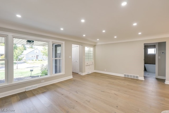 spare room with light hardwood / wood-style floors, crown molding, and a wealth of natural light