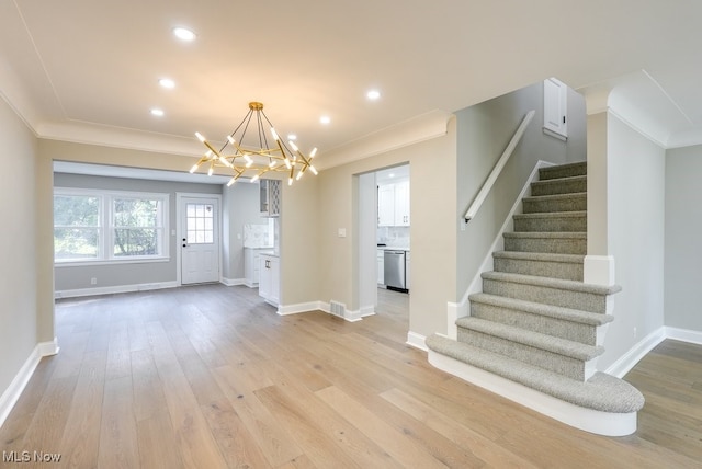 foyer entrance featuring ornamental molding, light hardwood / wood-style flooring, and a chandelier