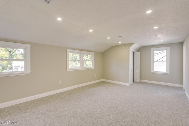 basement featuring a healthy amount of sunlight, a textured ceiling, and light colored carpet