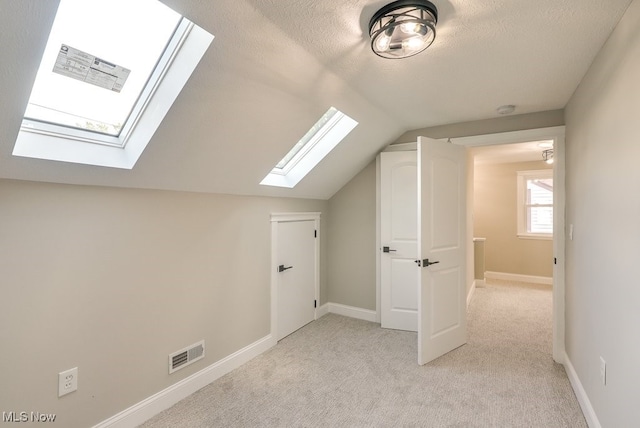 additional living space with vaulted ceiling, light carpet, and a textured ceiling