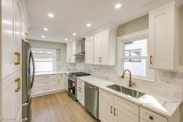 kitchen featuring white cabinets, light hardwood / wood-style flooring, sink, wall chimney exhaust hood, and stainless steel appliances