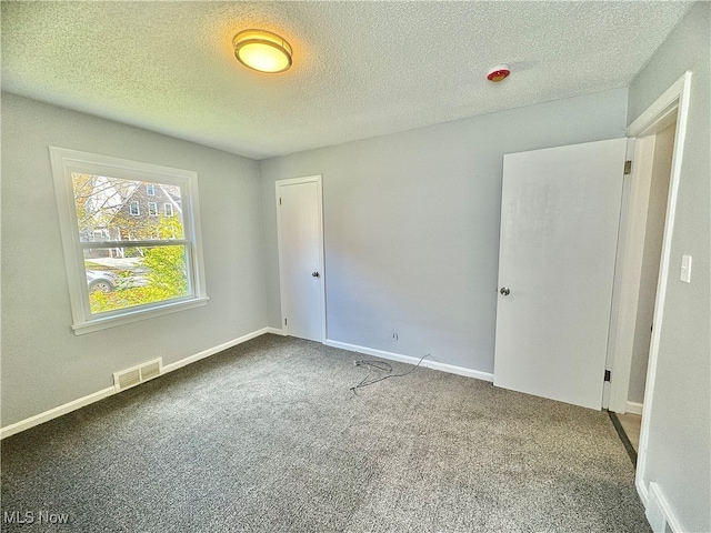 carpeted empty room with a textured ceiling