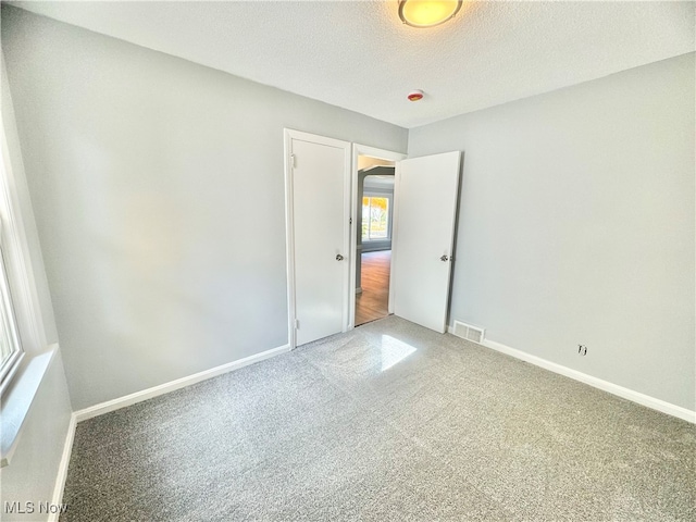 unfurnished room featuring carpet and a textured ceiling