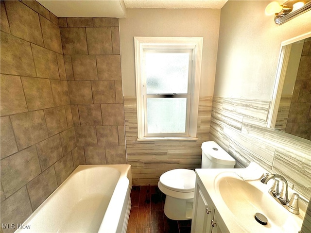 bathroom featuring a bath, hardwood / wood-style floors, toilet, tile walls, and vanity