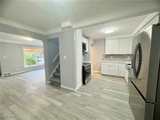 kitchen with decorative backsplash, stainless steel appliances, light wood-type flooring, white cabinetry, and a textured ceiling