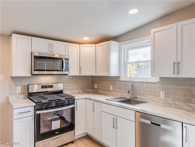 kitchen with white cabinetry, tasteful backsplash, stainless steel appliances, and sink