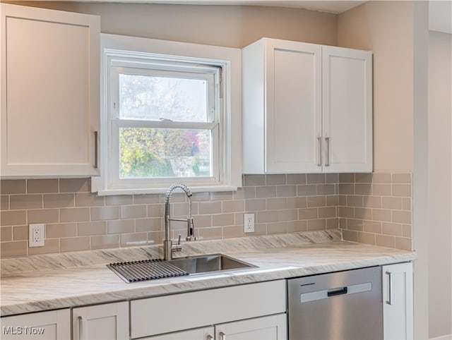 kitchen with decorative backsplash, white cabinetry, stainless steel dishwasher, and sink