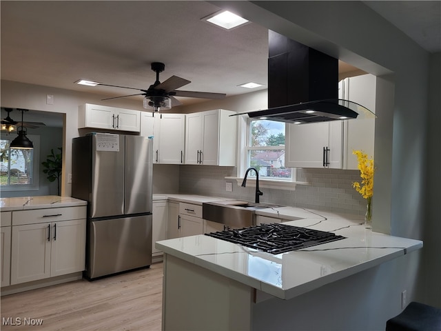 kitchen featuring light wood-type flooring, island exhaust hood, kitchen peninsula, stainless steel fridge, and white cabinetry