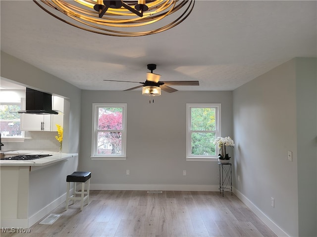 interior space featuring exhaust hood, white cabinetry, and a healthy amount of sunlight