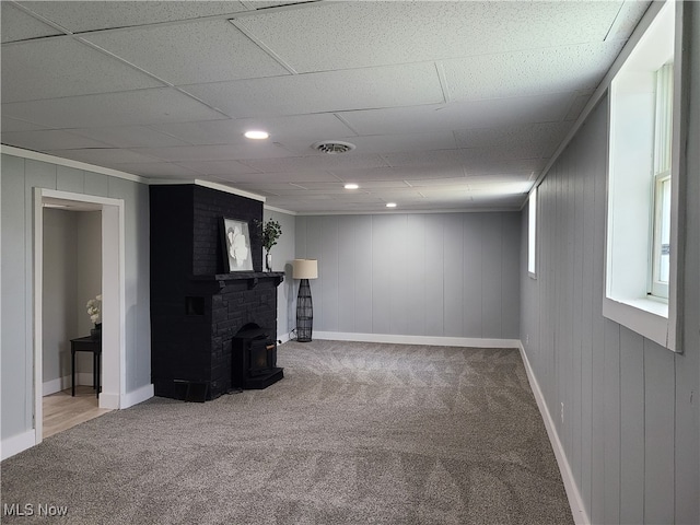 basement featuring carpet flooring, a wood stove, and wooden walls