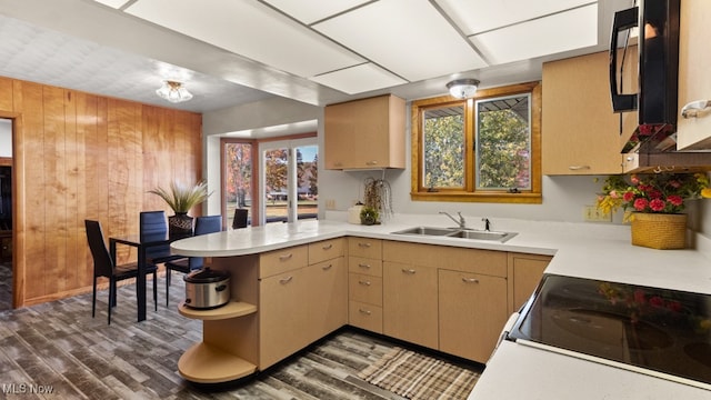 kitchen with kitchen peninsula, wooden walls, dark wood-type flooring, white range oven, and sink