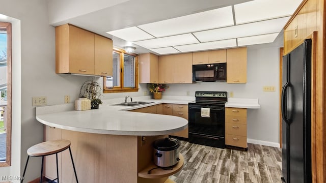 kitchen featuring sink, black appliances, kitchen peninsula, and a healthy amount of sunlight