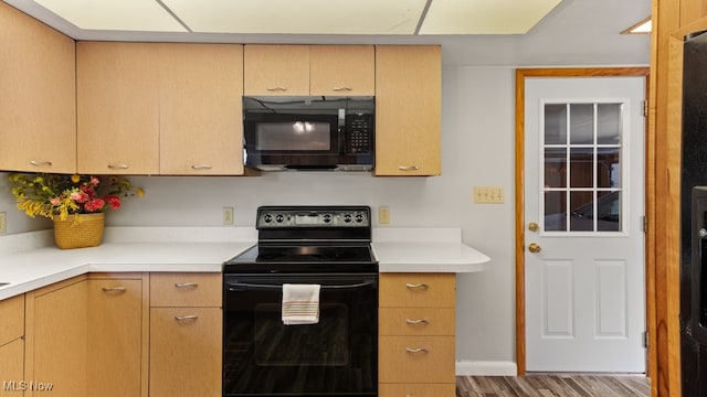 kitchen featuring light brown cabinetry, black appliances, and hardwood / wood-style floors