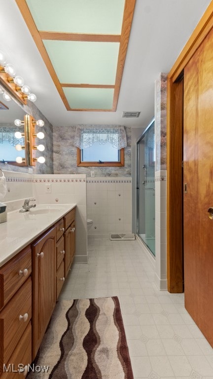 bathroom with tile walls, vanity, and an enclosed shower