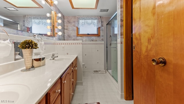 bathroom with tile walls, vanity, toilet, and walk in shower