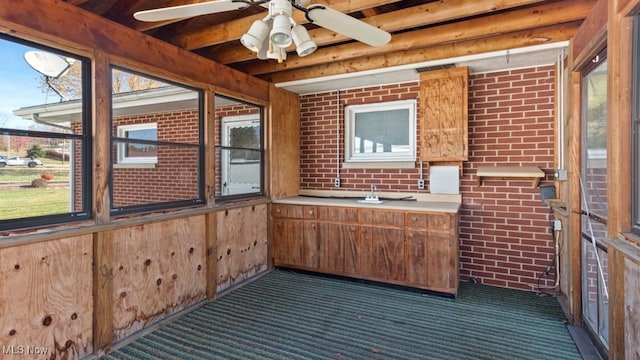 unfurnished sunroom featuring a healthy amount of sunlight, beamed ceiling, and ceiling fan