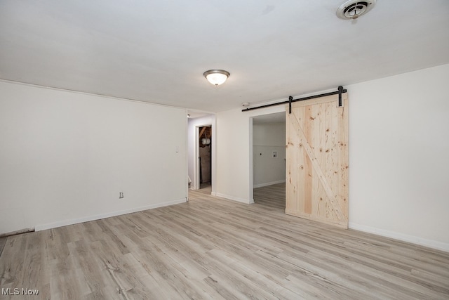 interior space with light hardwood / wood-style flooring, a walk in closet, and a barn door