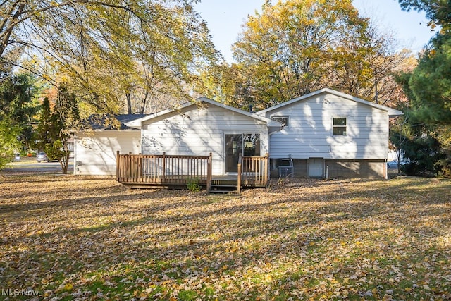 back of property featuring a wooden deck and a lawn