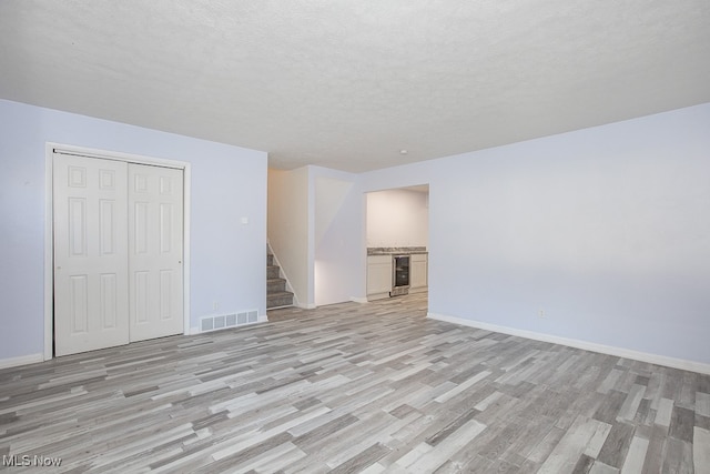 unfurnished living room with a textured ceiling and light wood-type flooring