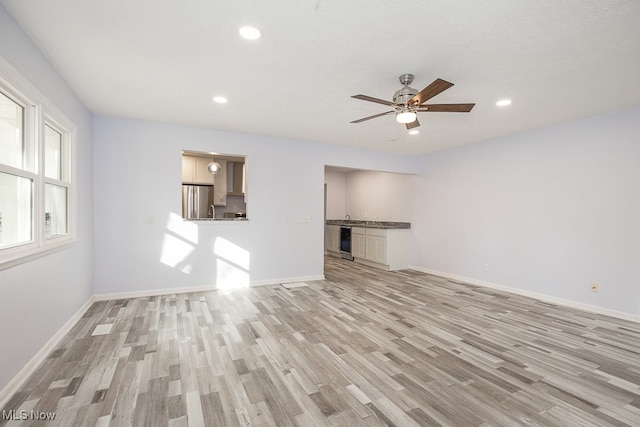 unfurnished living room featuring light hardwood / wood-style floors, a textured ceiling, and ceiling fan