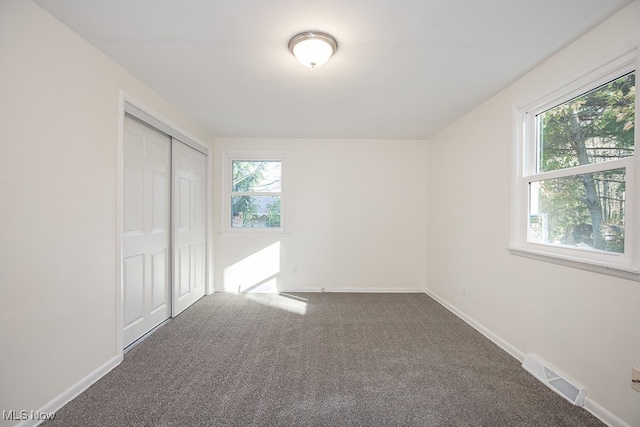 unfurnished bedroom featuring a closet and dark colored carpet