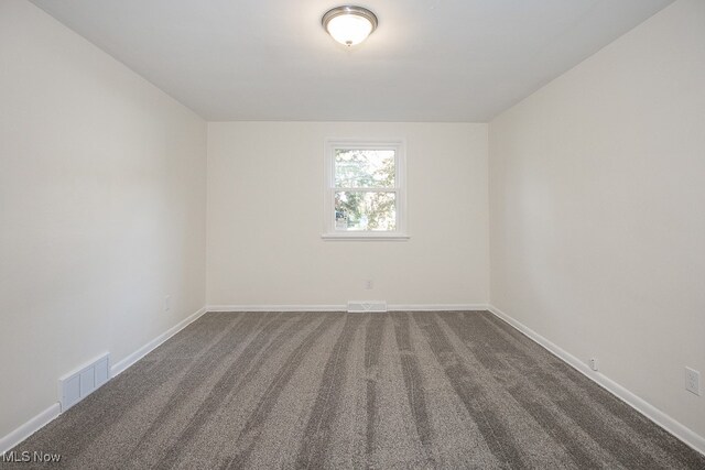 unfurnished room with dark colored carpet