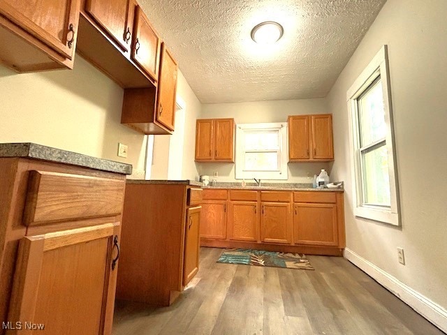 kitchen featuring a textured ceiling, sink, and light wood-type flooring