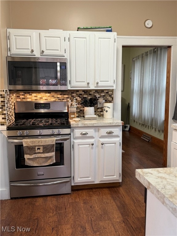 kitchen featuring appliances with stainless steel finishes, white cabinets, tasteful backsplash, and dark hardwood / wood-style floors