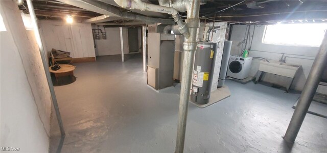 basement featuring water heater, heating unit, and washer / clothes dryer