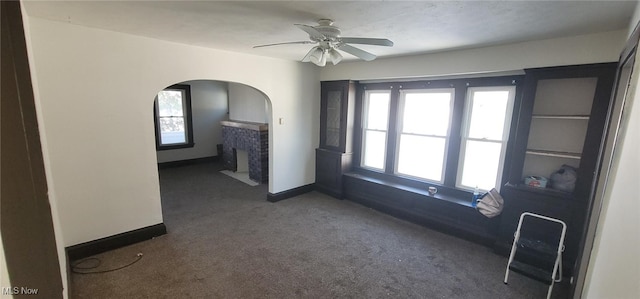 unfurnished room with ceiling fan, plenty of natural light, and dark colored carpet