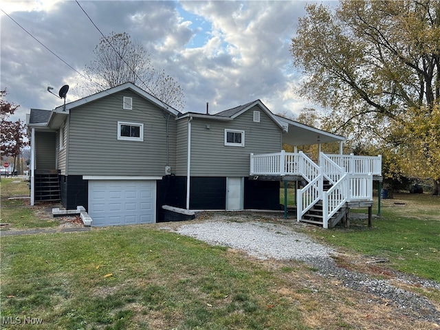 rear view of house with a yard, a wooden deck, and a garage