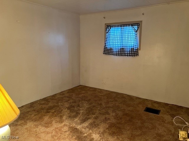 carpeted spare room featuring crown molding