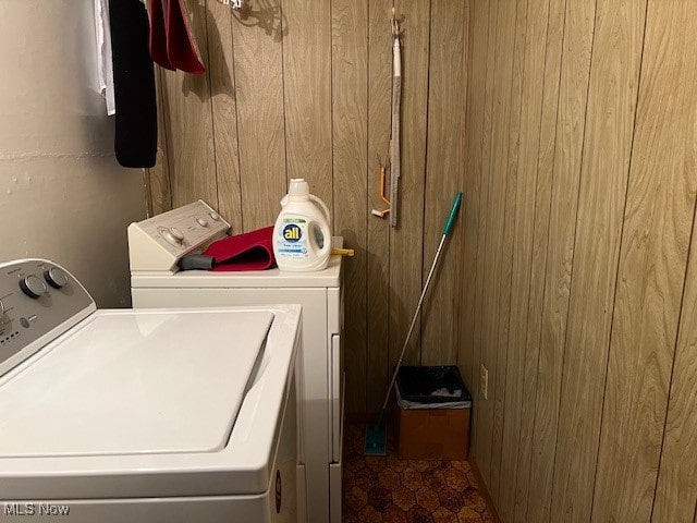 clothes washing area featuring wood walls and washing machine and dryer