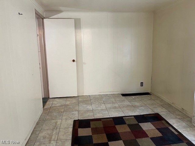 tiled empty room featuring wood walls