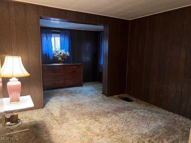 carpeted empty room with wood walls