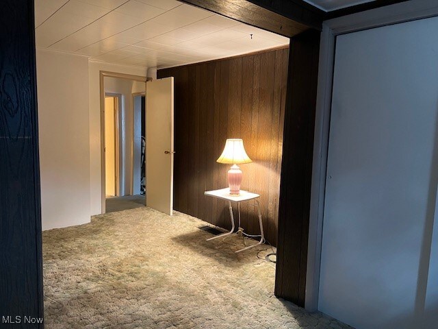 hall featuring carpet flooring and wood walls