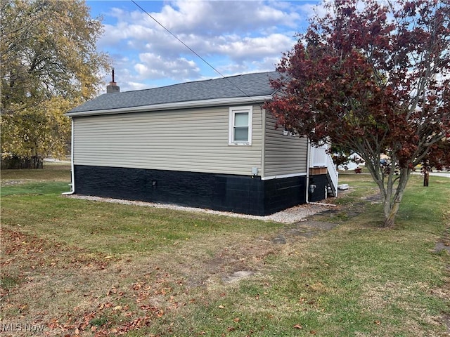 view of home's exterior featuring roof with shingles and a yard