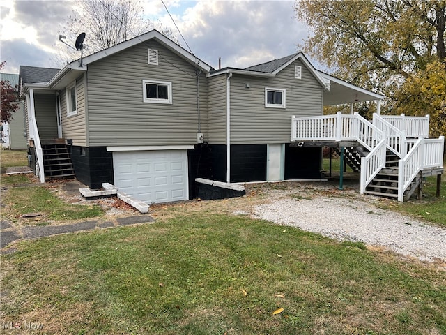 rear view of property featuring a deck, a yard, and a garage