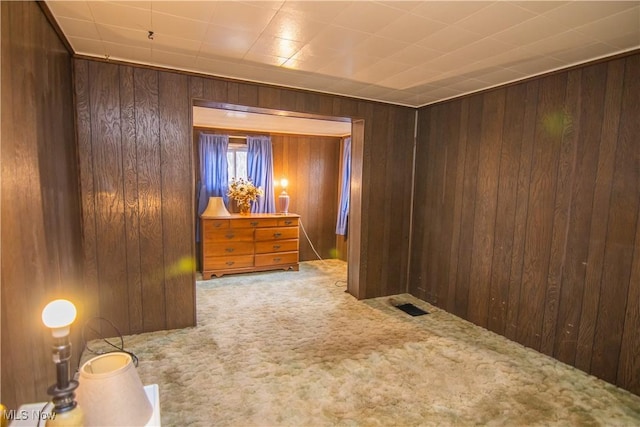 carpeted spare room with wood walls and visible vents