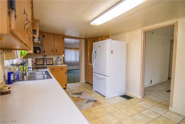 kitchen featuring light tile patterned floors, open shelves, light countertops, freestanding refrigerator, and a sink