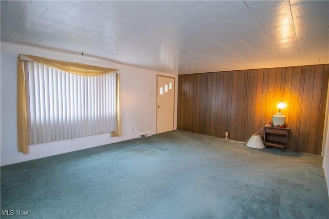 carpeted empty room with wooden walls and visible vents