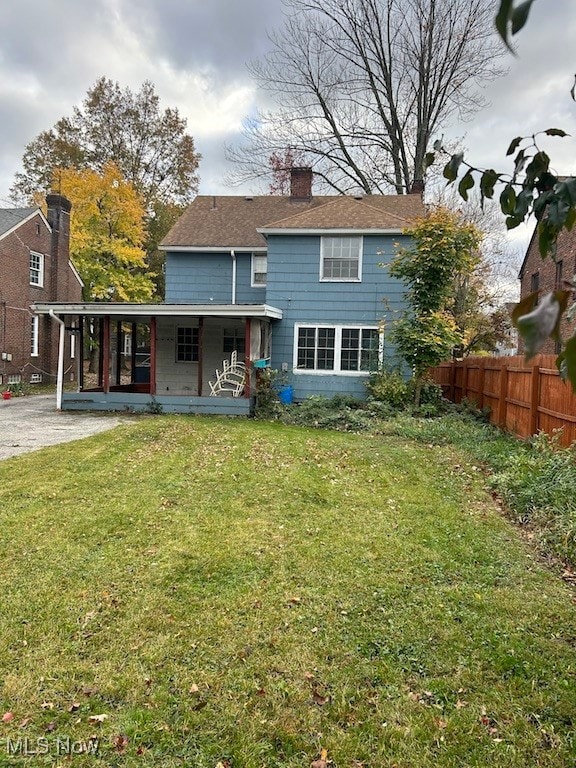 rear view of house with a porch and a lawn